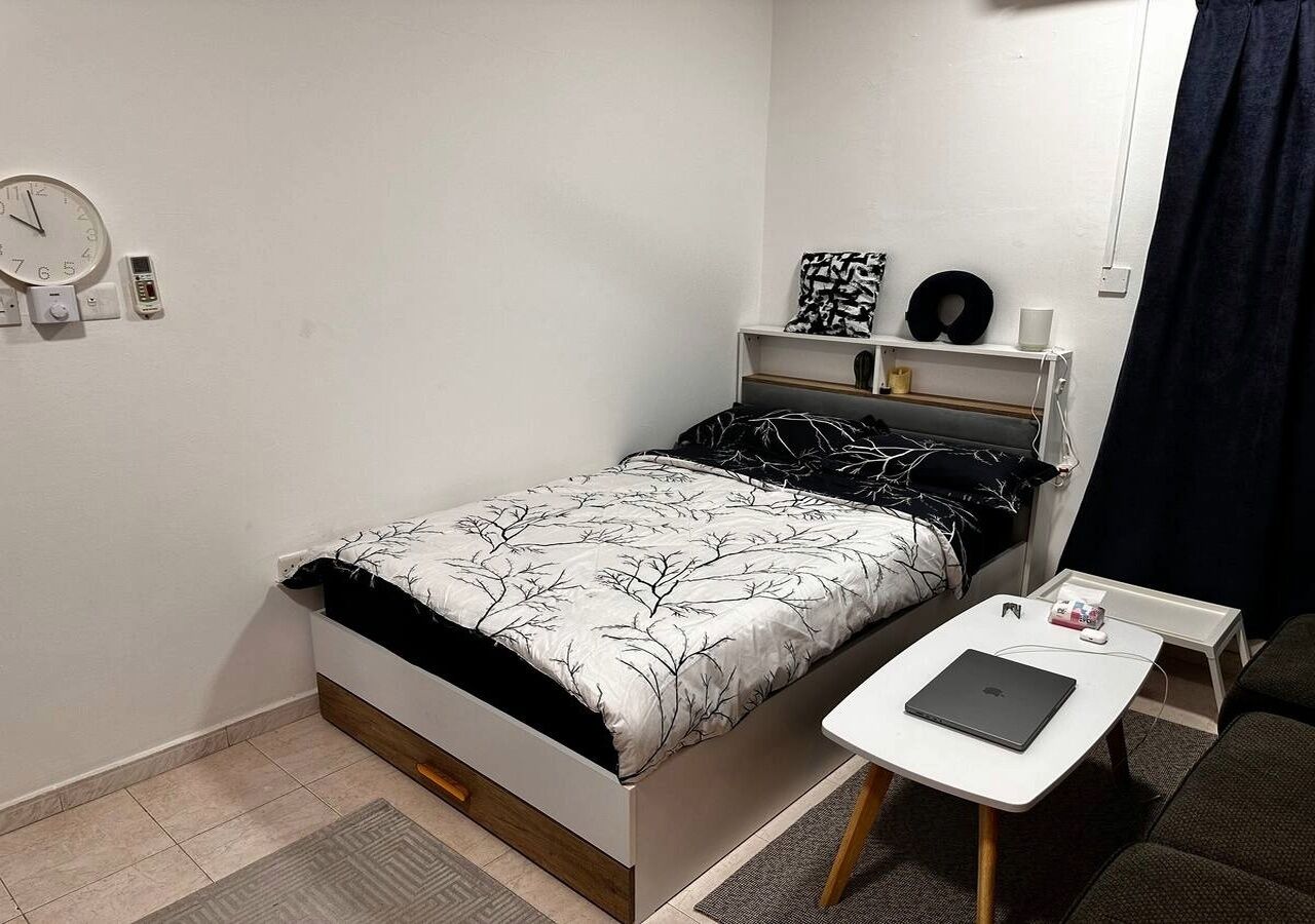 Une petite chambre à coucher moderne, avec un lit, une table de chevet et un ordinateur portable.