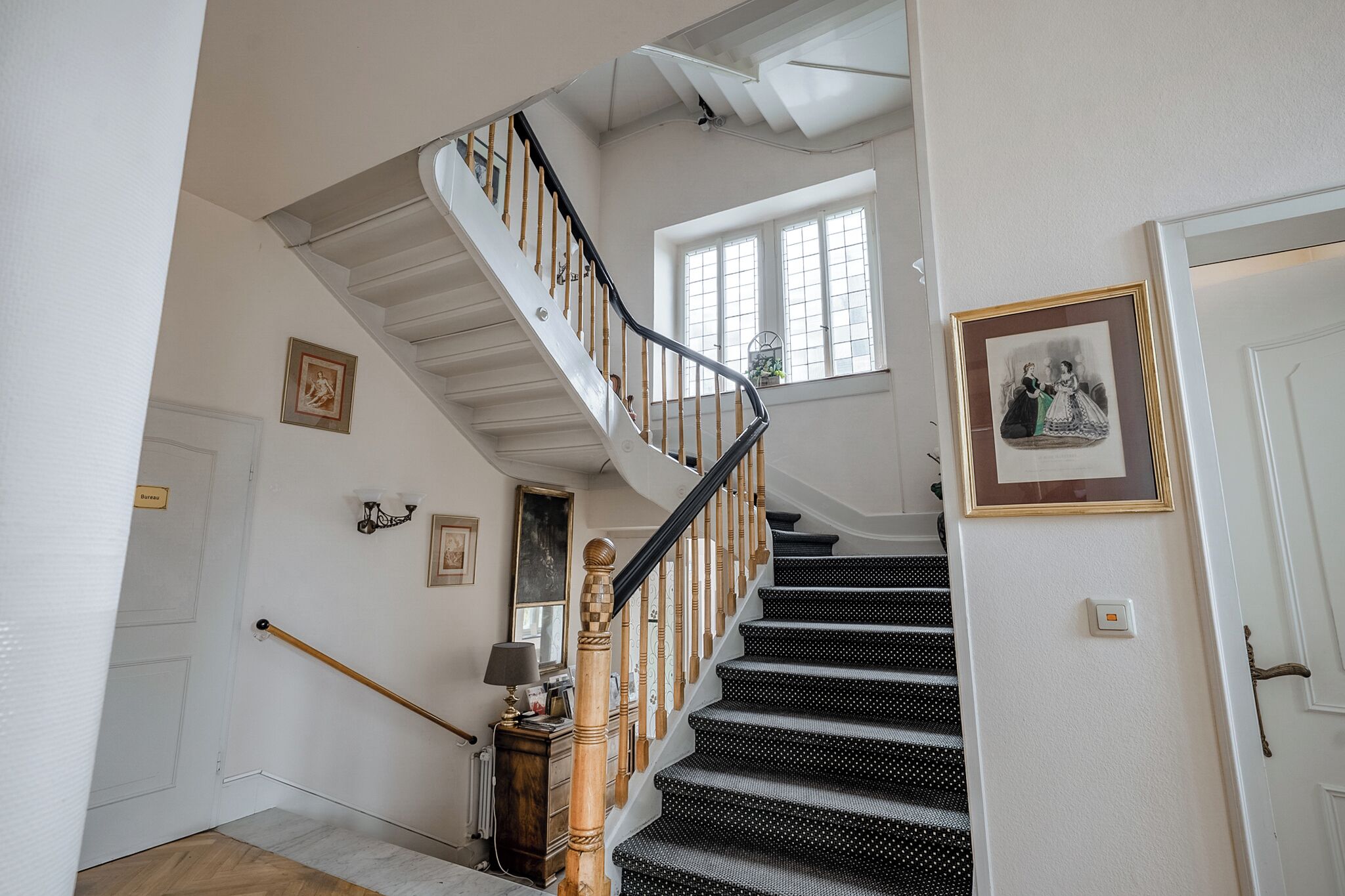 A staircase with a wooden handrail and black carpeted steps.