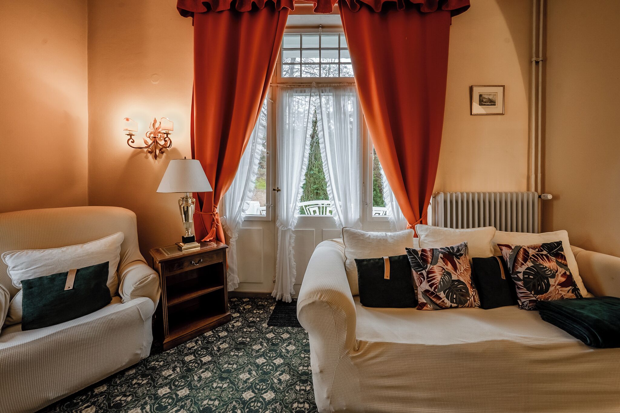 Une pièce avec deux canapés, une table avec une lampe et une fenêtre avec des rideaux.