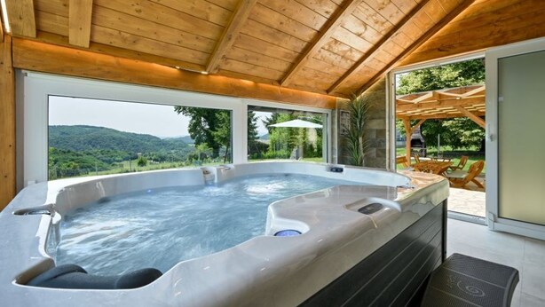 Una vasca idromassaggio in una baita di legno con vista sulle montagne.