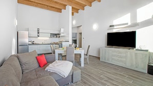 A modern living space with a sofa, a dining table, and a TV. - Tana Delle Volpi Alpine Apt for 6 (Cesana Torinese)