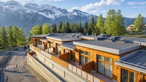 A modern hotel with multiple floors, large windows, and a view of snow-capped mountains. - Tana Delle Volpi Alpine Apt for 6 (Cesana Torinese)