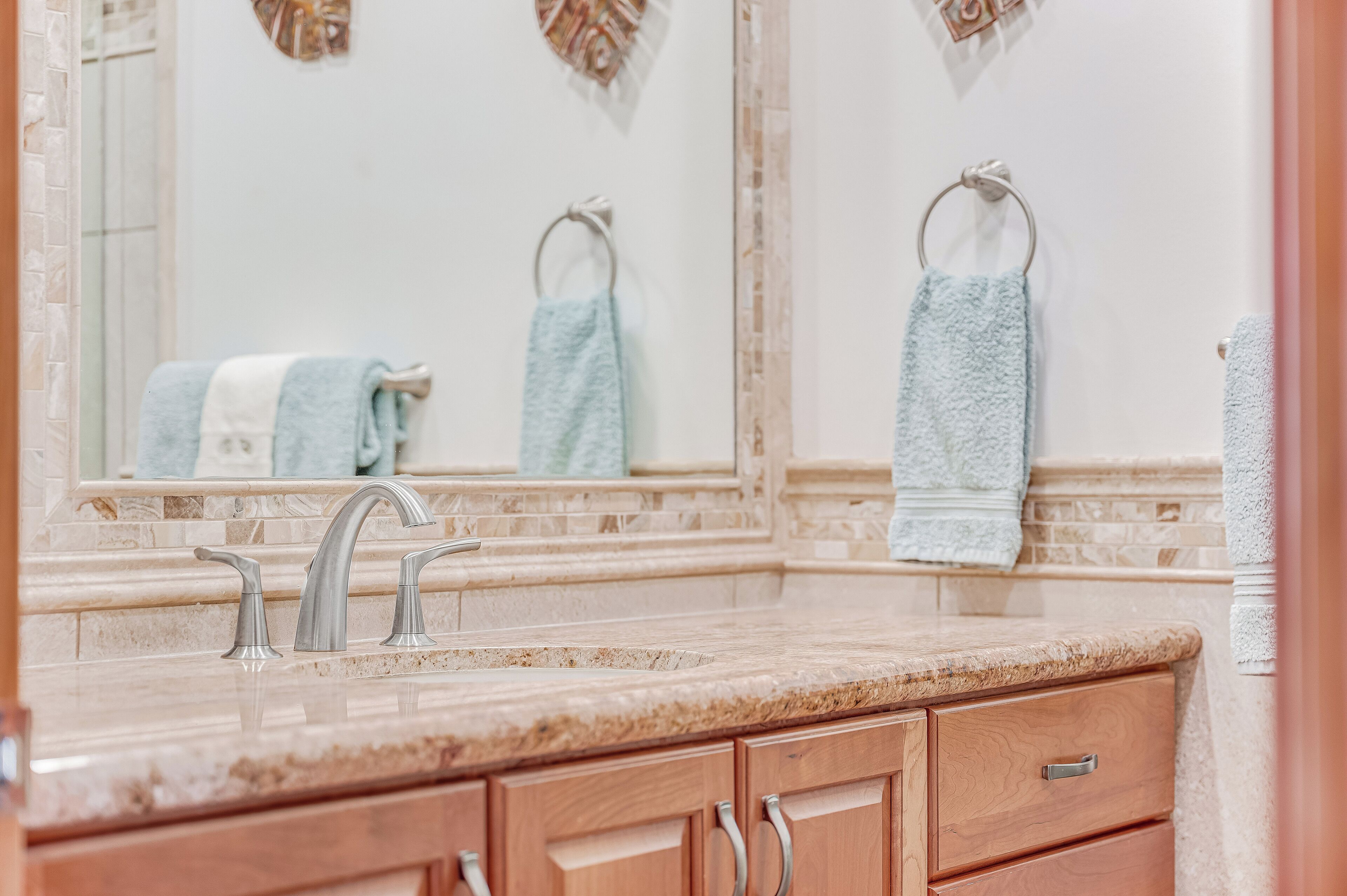 Une salle de bain avec un comptoir en marbre, deux lavabos et des meubles en bois.