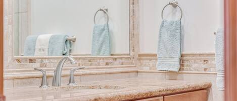 Une salle de bain avec un comptoir en marbre, deux lavabos et des meubles en bois.