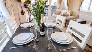 A dining table set for four with white plates, cutlery, and a bottle of Moët & Chandon champagne. - Rosefinch Cabin (Scarborough)