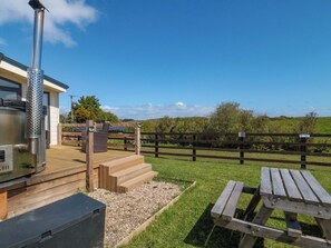 A patio with a wood-burning stove, a picnic table, and a wooden fence. - Rosefinch Cabin (Scarborough)