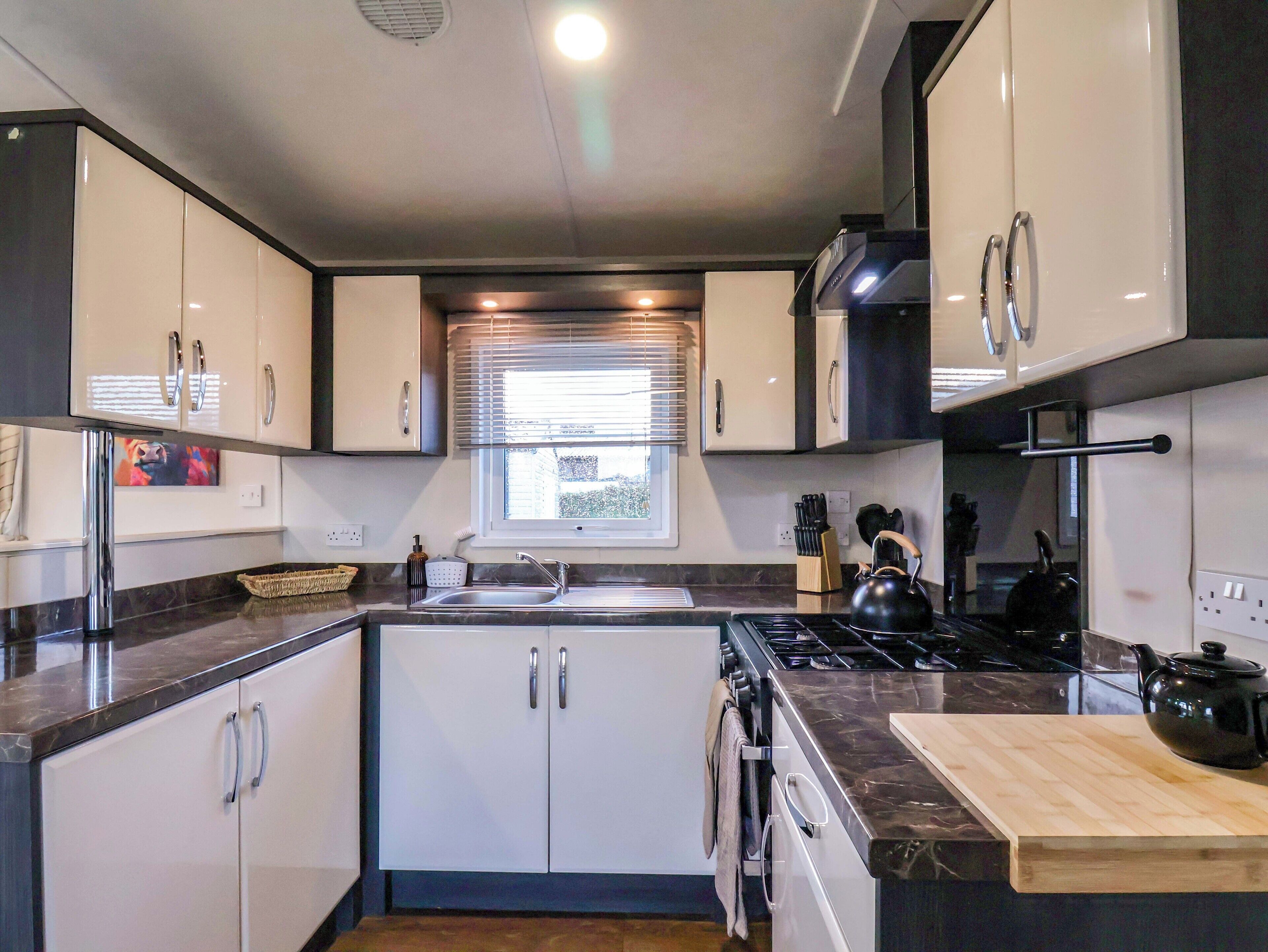 A modern kitchen with white cabinets, a black stove, and a wooden countertop.