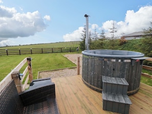 A hot tub on a wooden deck with a wooden fence in the background. - Swift Cabin (Scarborough)