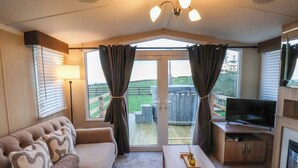 Een gezellige woonkamer met een bank, een salontafel, een televisie en een schuifdeur die leidt naar een terras.