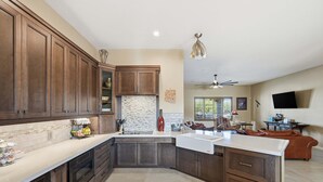 A spacious kitchen with dark wood cabinets, a large island, and a tiled backsplash. - Alanamari Desert Estate, Pool, Spa, Casita 4 Bedroom Home (Phoenix)