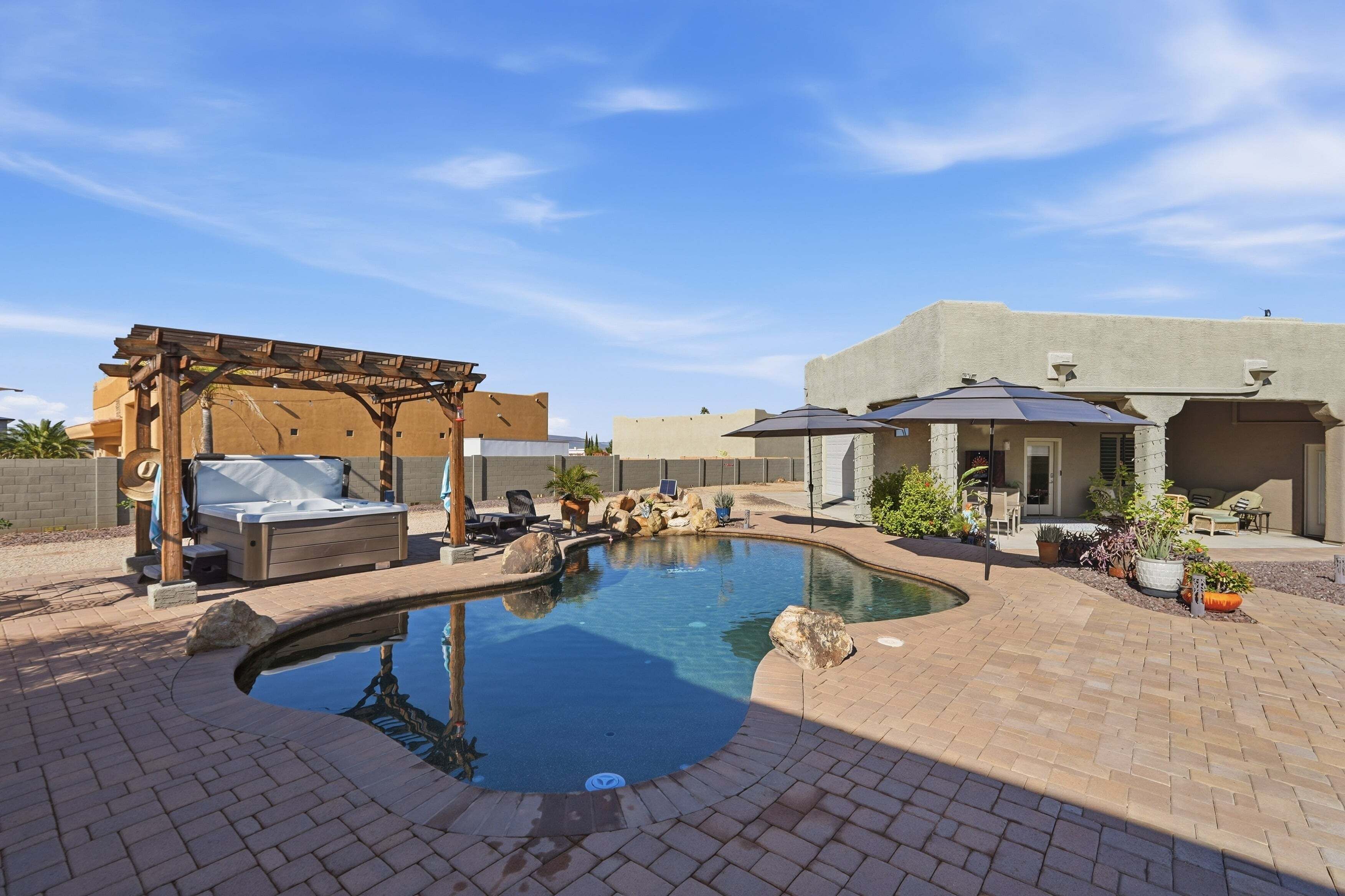 Ein Garten mit Schwimmbad, einer Pergola mit Grill und Gartenmöbeln.
