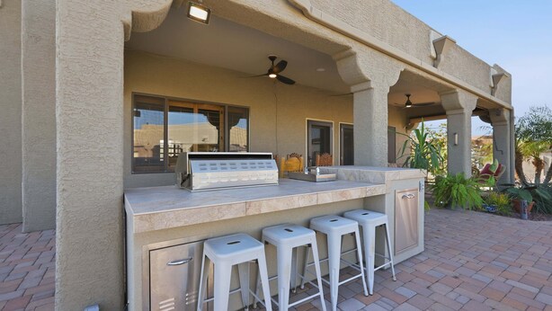 An outdoor bar area with a countertop, stools, and a ceiling fan. - Alanamari Desert Estate, Pool, Spa, Casita 4 Bedroom Home (Phoenix)