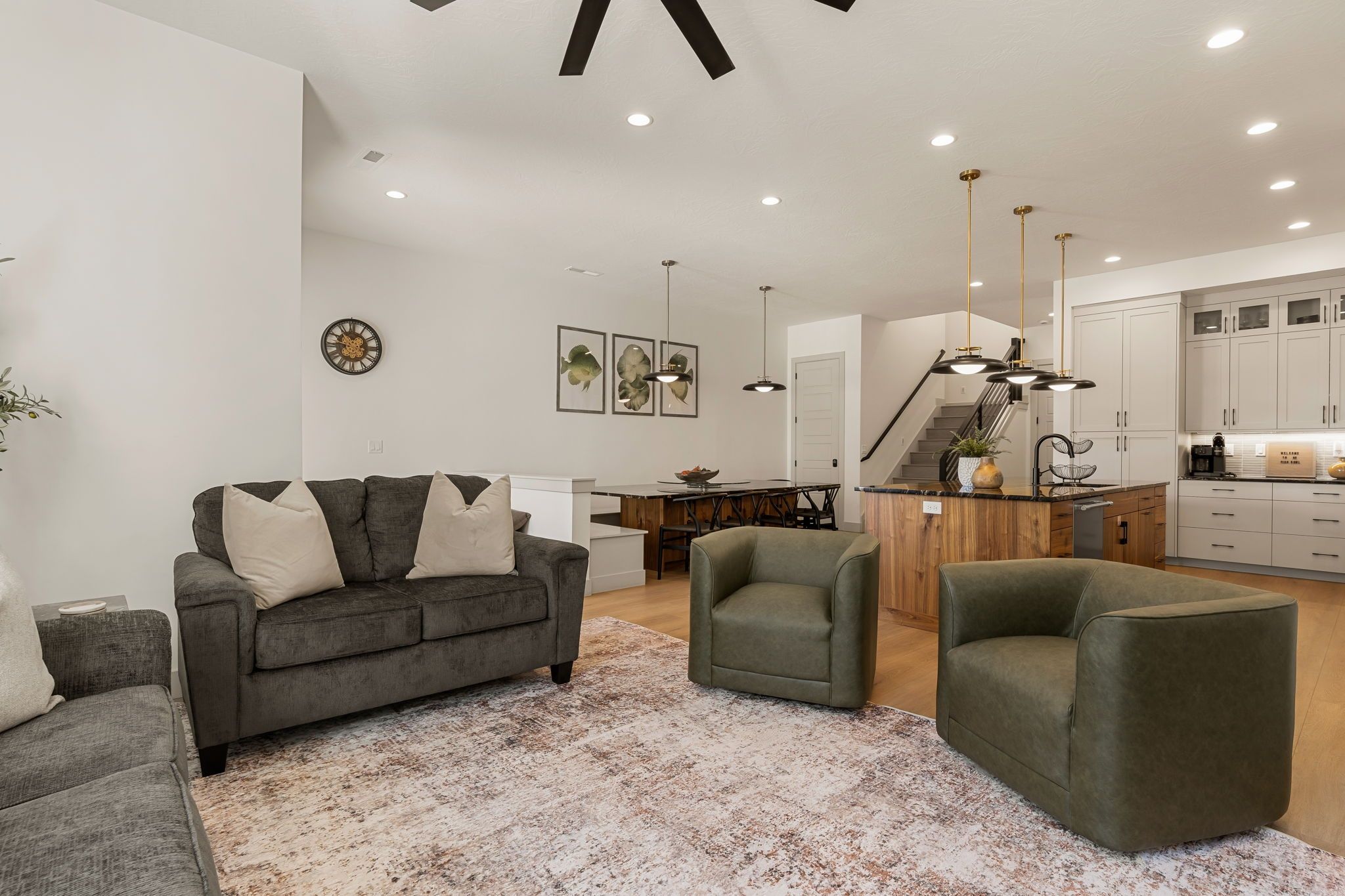 Un salon moderne avec un canapé gris, un fauteuil vert et une table à manger en bois.