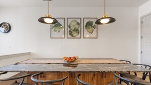 A dining area with a marble table, wooden chairs, and pendant lights. - The Fish Bowl 6 Bedroom Townhouse (St. George)