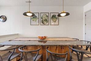 Zona pranzo con tavolo in marmo, sedie in legno e lampade a sospensione.