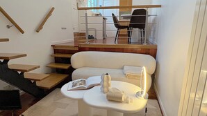 Een modern interieur met een trap, een bank, een tafel met een boek en een lamp.