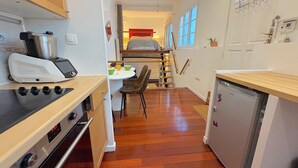 Een compacte keuken met een fornuis, een kleine koelkast en een eethoek met een tafel en stoelen.