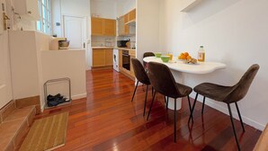 Een moderne keuken met houten kasten, een eettafel met vier stoelen en een klein schiereiland met een spoelbak.
