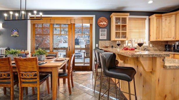 A kitchen with wooden cabinets, a bar area, and a dining table with chairs. - Town Pointe A105 3 Bedroom Condo (Park City)