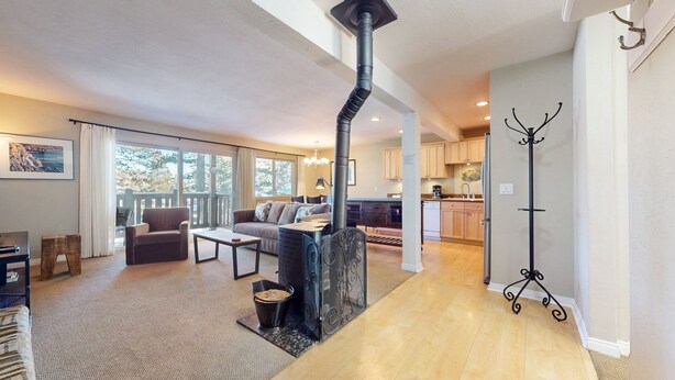 A spacious living area with a fireplace, a sofa, a coffee table, and a view of the outside. - Western Slopes Villas #7 1 Bedroom Condo (Mammoth Lakes)