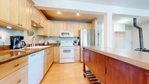 A modern kitchen with wooden cabinets, a stainless steel refrigerator, a microwave, and a coffee maker. - Western Slopes Villas #7 1 Bedroom Condo (Mammoth Lakes)