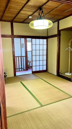 A traditional Japanese room with tatami flooring, a shoji screen door, and a hanging light fixture. - Spacious family-friendly 4-bedroom house overlooking beautiful central Atami (Atami)