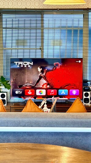 Een televisie waarop een programma met de titel 'TRON' wordt vertoond, met een digitale klok die 12:59 aangeeft.