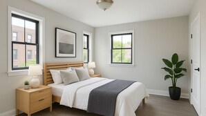 Ein Schlafzimmer mit einem Bett, Nachttischen, Lampen, einer Topfpflanze und Bildern an der Wand.