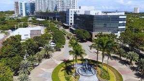 A modern building complex with a central plaza featuring a sculpture. - MCollection - Mactan Island Stay Near Beach and Airport (Lapu-Lapu)