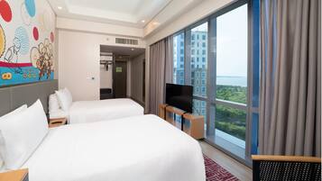 A hotel room with two beds, a TV, and a large window with a city view.