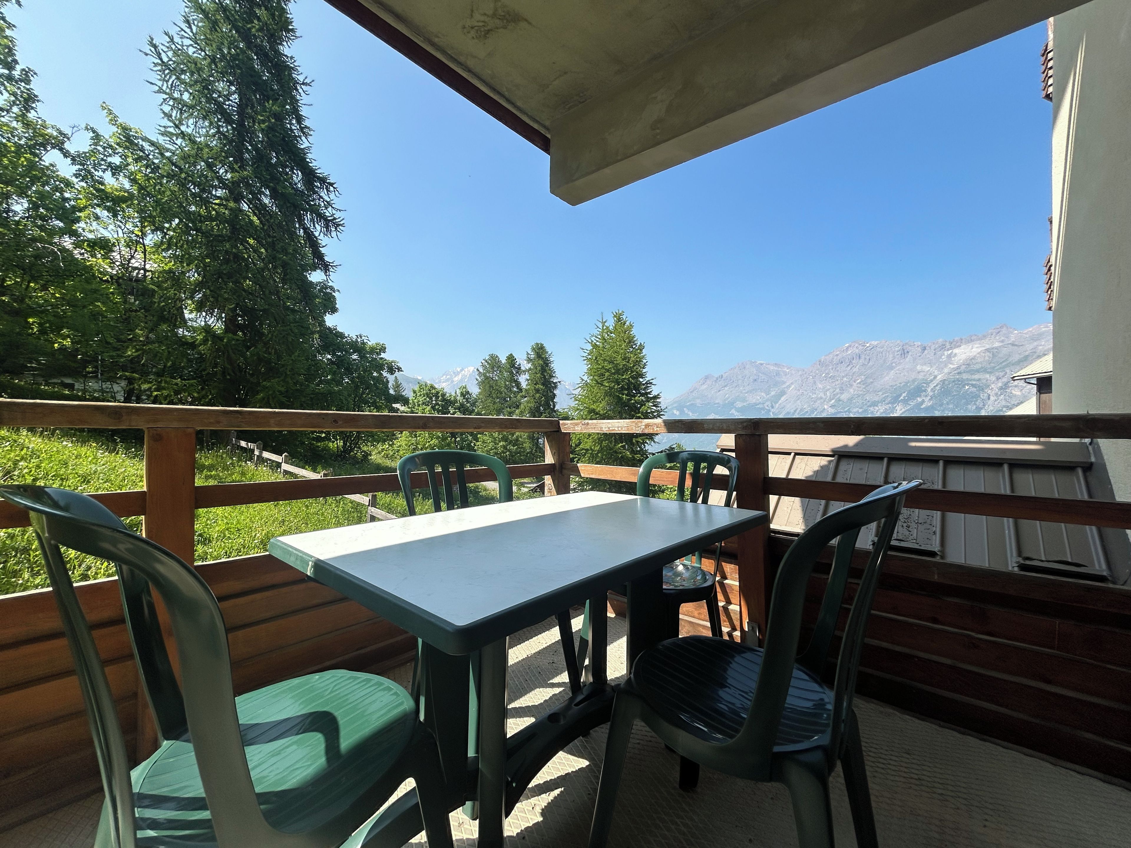 Una terraza con una mesa y sillas, con vistas a un paisaje montañoso.