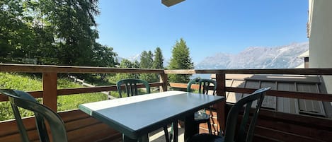 A terrace with a table and chairs, overlooking a mountainous landscape.
