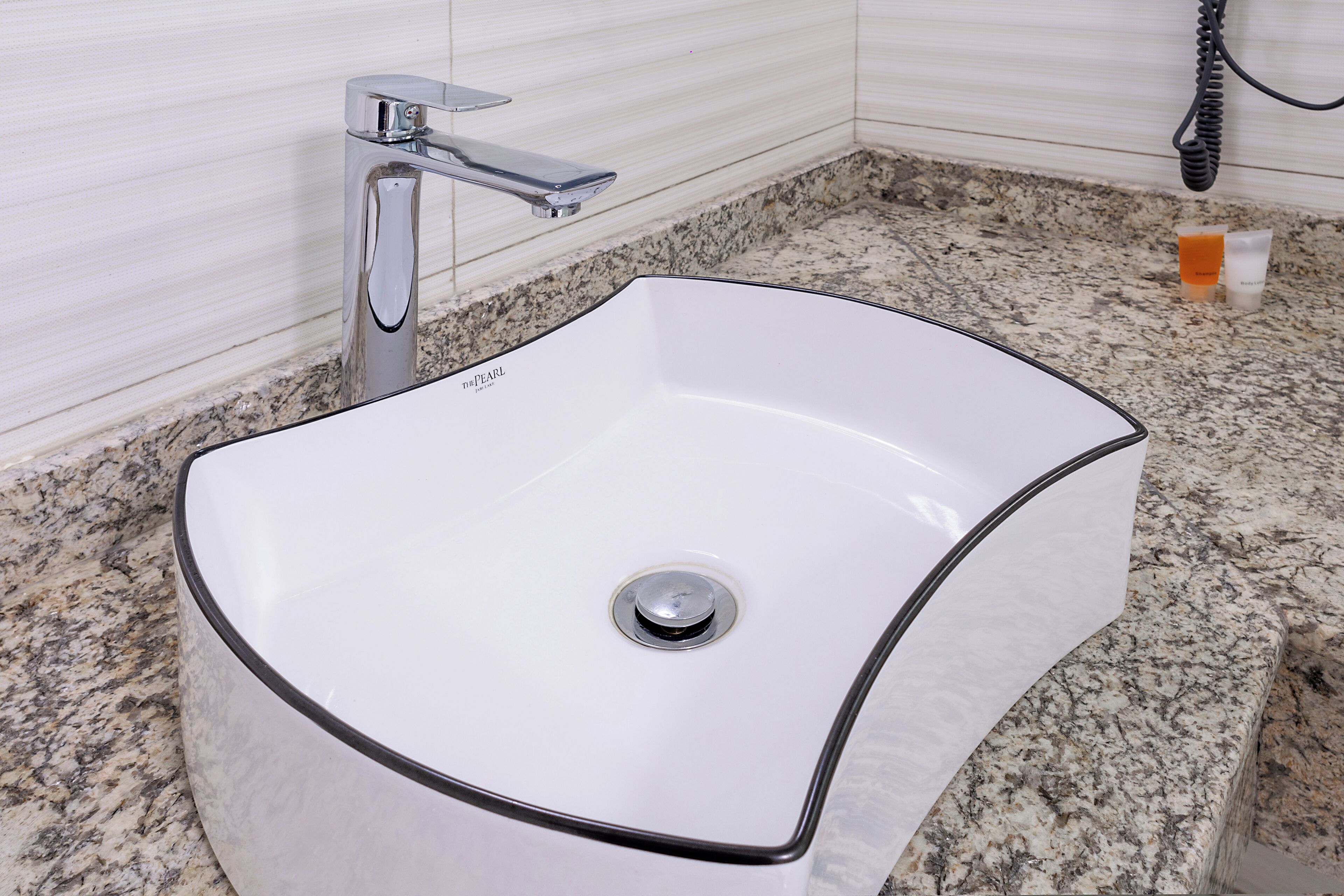 A bathroom with a white sink, chrome faucet, and granite countertop.