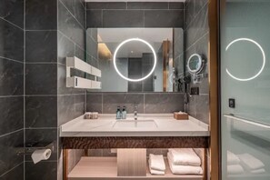 Un baño moderno con un espejo grande, estantes integrados, un mueble de tocador con lavabo y un perchero para toallas.
