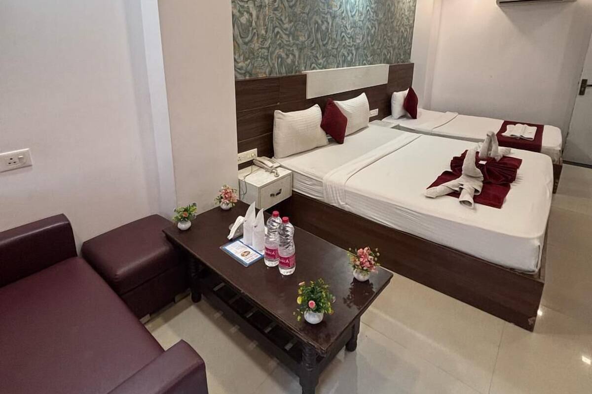 Une chambre d’hôtel avec un grand lit, un canapé, une petite table avec des commodités et un mur décoratif.