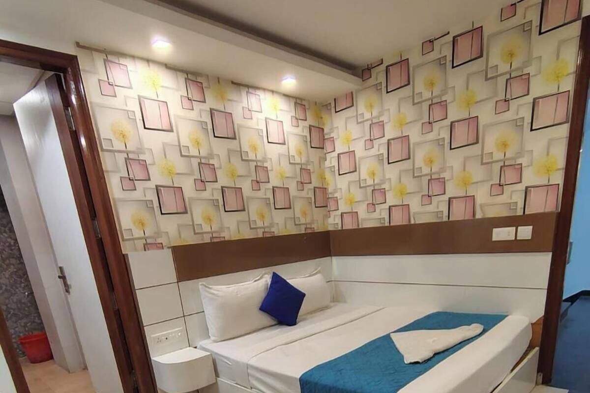 Une chambre à coucher avec un lit, des tables de chevet, une commode et un mur décoré d’un motif.