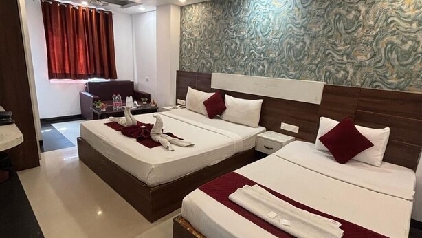 Ein Hotelzimmer mit zwei Betten, einem Deckenventilator, einer Wand mit Marmoroptik und einem roten Vorhang.