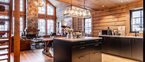 Una cocina moderna con chimenea de piedra, vigas de madera y ventanas amplias.