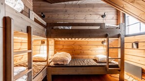 Une chambre avec un lit superposé, des murs en bois et une fenêtre.