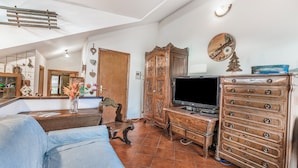 A living room with a sofa, wooden cabinet, TV stand, and decorative items. - Champlas Suite - Balcony Views, Sleeps 4 (Sestriere)