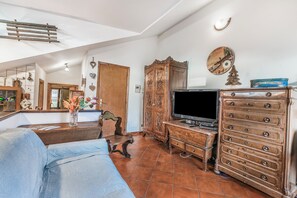 A living room with a sofa, wooden cabinet, television, and decorative items. - Champlas Suite (Sestriere)