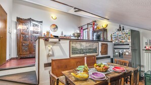 A dining area with a wooden table set for a meal, a refrigerator with magnets, and a view of the city through a window. - Champlas Suite - Balcony Views, Sleeps 4 (Sestriere)