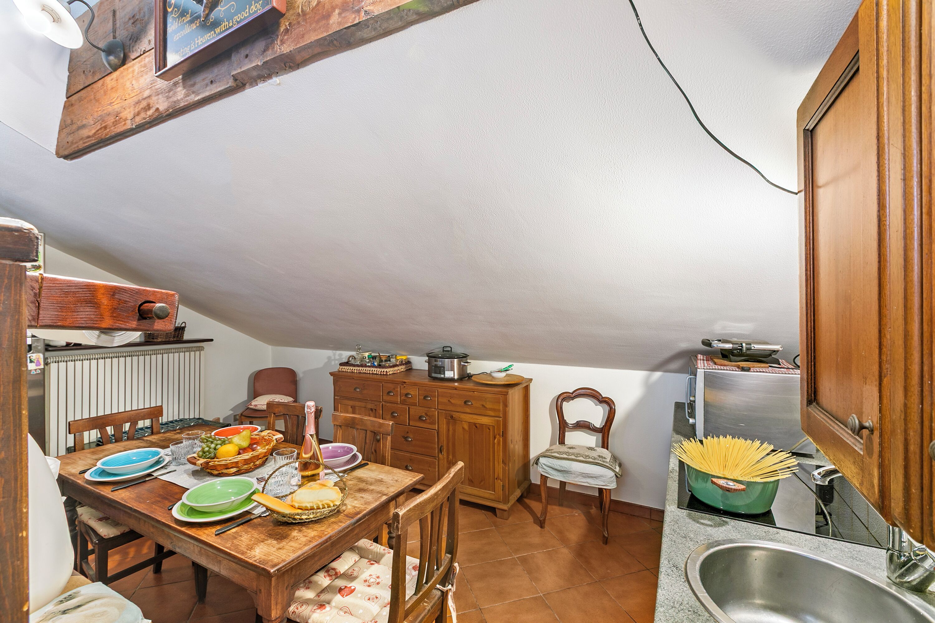 A cozy kitchen with wooden cabinets, a dining table set with plates and bowls, and a sink.