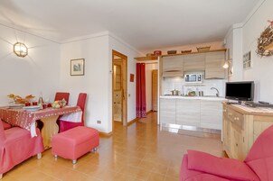 A dining area with a table set for four, a kitchen with modern appliances, and a living area with a television.
