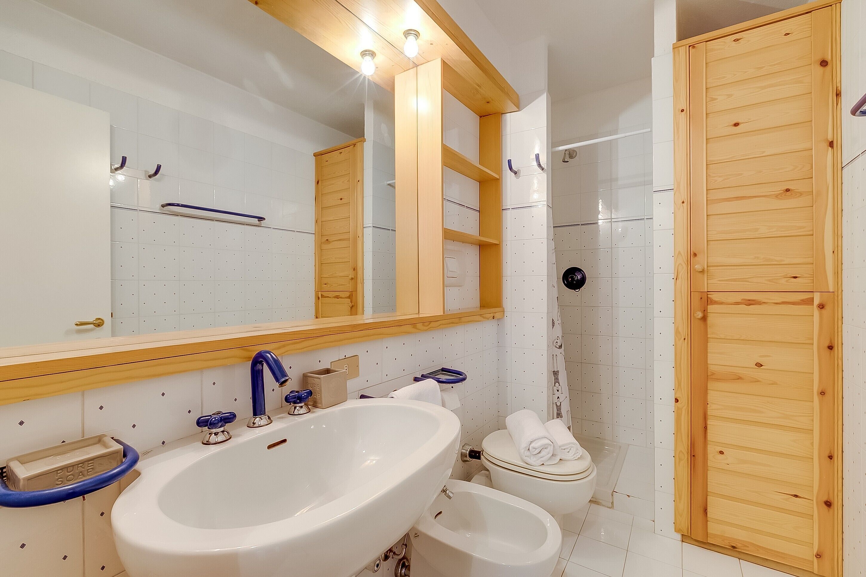 A bathroom with a large sink, toilet, and shower area.