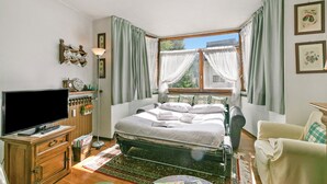 A bedroom with a bed, a television, a dresser, and a window with curtains. - Appartamento Aricami With Balcony & Mountain View (Sestriere)