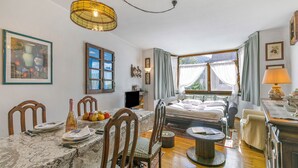 A room with a dining table set for two, a bed with a canopy, a lamp, and a window with curtains. - Appartamento Aricami With Balcony & Mountain View (Sestriere)