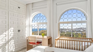 A bedroom with a bed, a desk, and a chair, with large arched windows offering a view of the sea and buildings. - Private Villa with Sea Views in Torreblanca, Fuengirola (Fuengirola)
