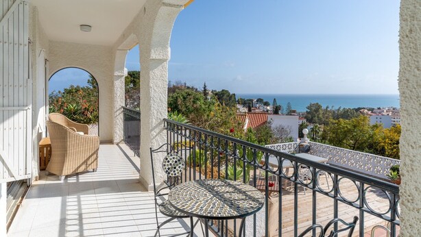 A balcony with a view of the sea, a wicker chair, a mosaic table, and a white door. - Private Villa with Sea Views in Torreblanca, Fuengirola (Fuengirola)
