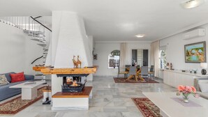 A modern living room with a fireplace, a staircase, a dining area, and a kitchen. - Private Villa with Sea Views in Torreblanca, Fuengirola (Fuengirola)